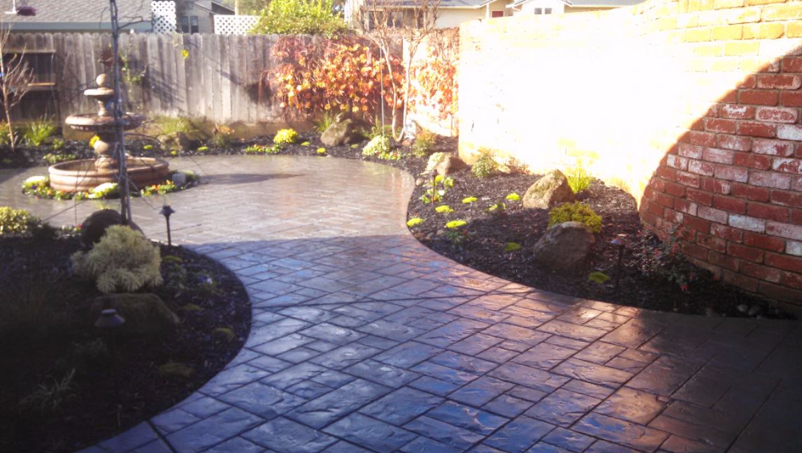 picture of a stamped and stained patio with a waterfall nearby