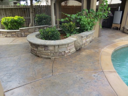 This is a stacked stone garden box and stamped and stained concrete pool deck
