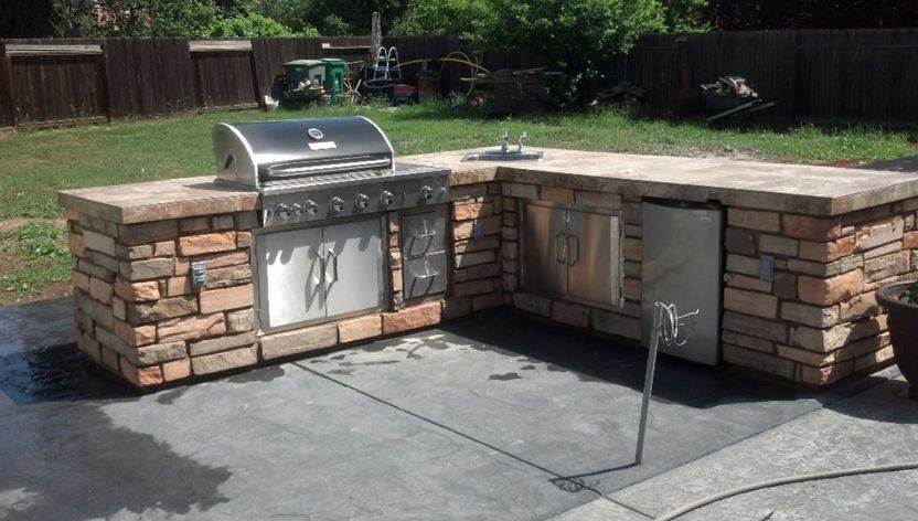 picture of a stacked stone counter set up with a barbecue and refrigerator installed within. Granite Bay, California